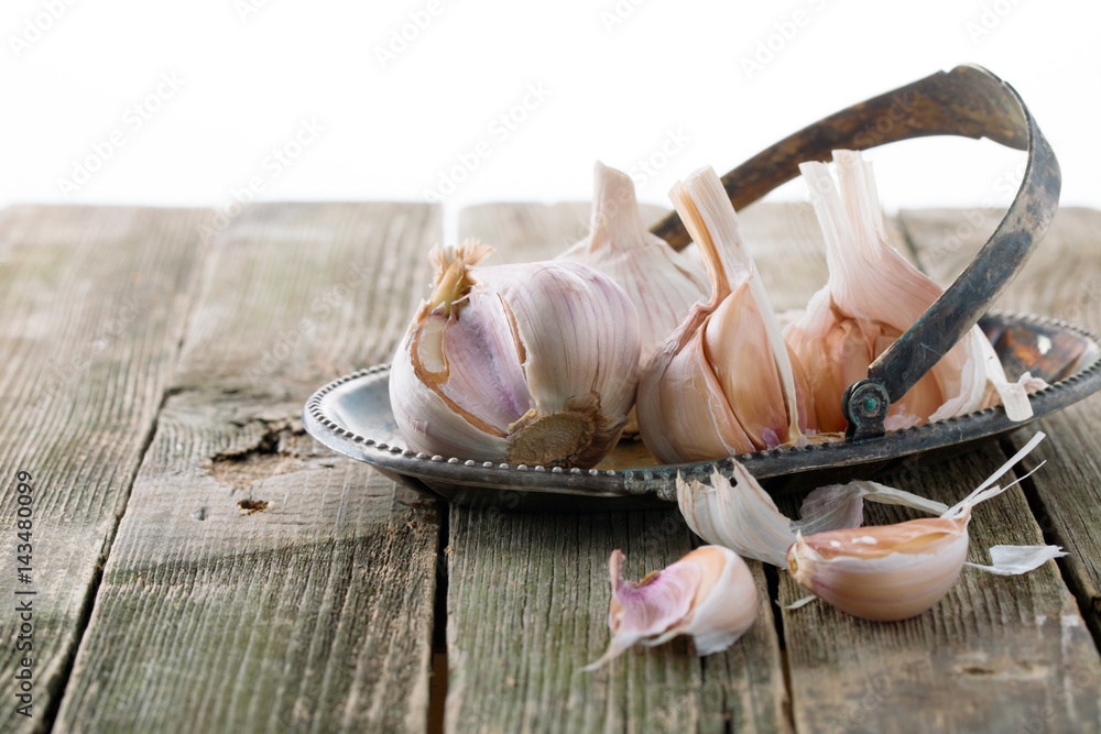 Garlic on an ancient metal dish on a wooden table Garlic on an ancient metal dish on a wooden table