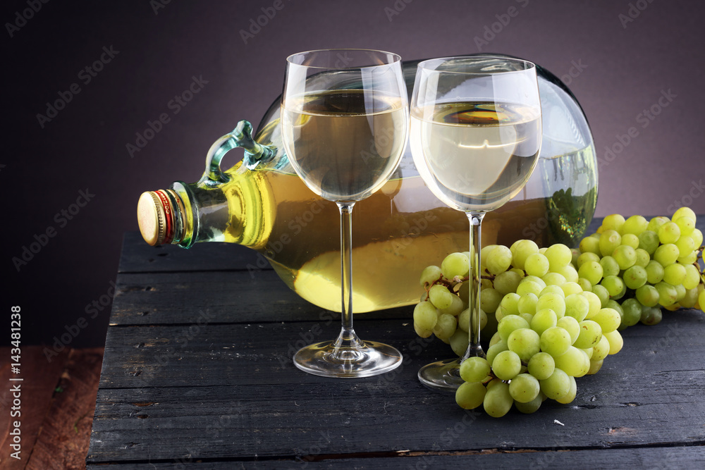 Obraz premium Bottle and glass of white wine, grape on wooden table