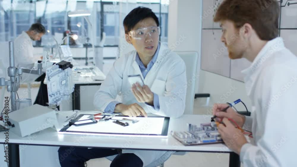 Electronics engineers working in lab building & testing electronic devices Electronics engineers working in lab building & testing electronic devices