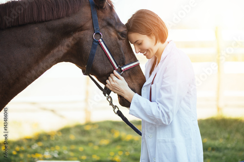 Vet petting a horse outdoors at ranch. 