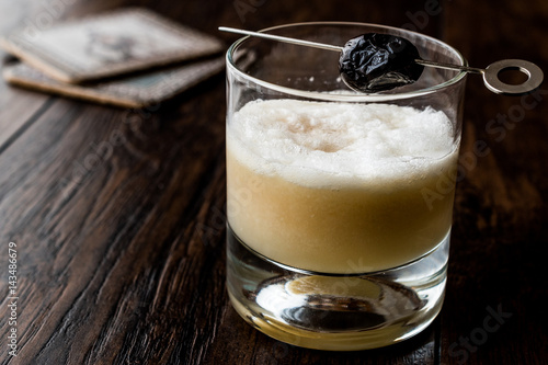 Whiskey sour cocktail served with olive.