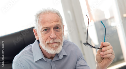 Portrait of senior businessman holding his glasses