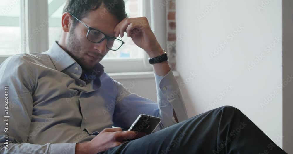 young caucasian business man detail relaxing on couch using smartphone indoor in modern industrial house. 4k handheld close up video shot young caucasian business man detail relaxing on couch using smartphone indoor in modern industrial house. 4k handheld close up video shot