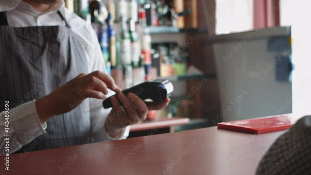 Man working in the bar accepting customer's cashless payment with credit card Man working in the bar accepting customer's cashless payment with credit card