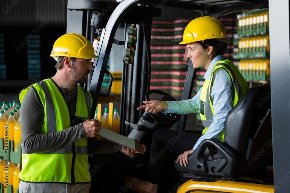 Male worker showing clipboard to female worker Male worker showing clipboard to female worker