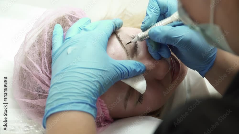 Closeup of beautician is making an eyebrow permanent makeup in salon Closeup of beautician is making an eyebrow permanent makeup in salon