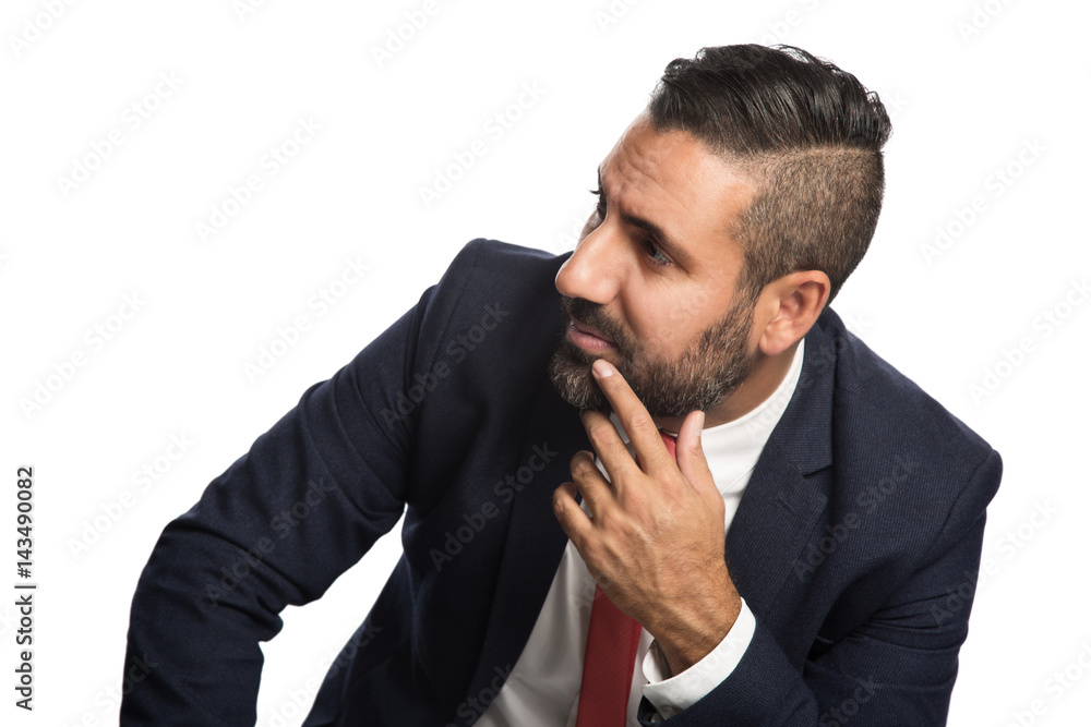 Handsome businessman in a blue suit and red tie, sitting down in front of a white background with his hand on knee. Handsome businessman in a blue suit and red tie, sitting down in front of a white background with his hand on knee.