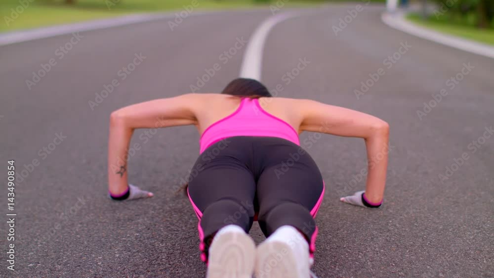 Push ups woman. Woman push ups on asphalt road. Back view of woman pushing on park road. Slim woman doing push up exercise. Fitness workout on park road. Sexy girl doing push ups outdoors