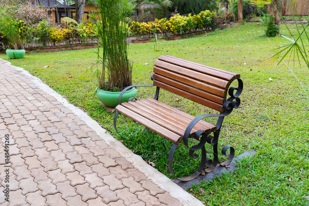 Wooden bench in garden or park outdoor with meadow.