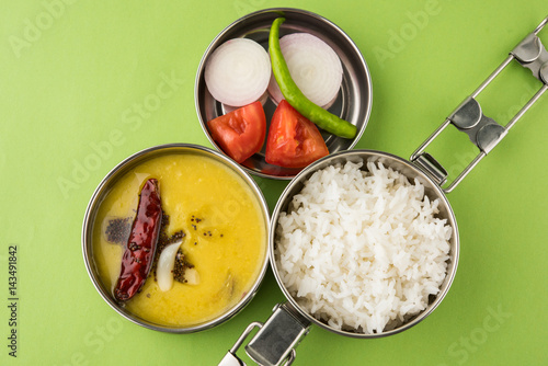 indian typical stainless steel lunch box or tiffin with north indian or maharashtrian food menu like chapati//roti, dal tadka, white rice and aloo / potato sabji / gobi or cauliflower sabji with salad