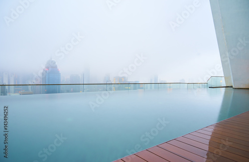 Swimming pool on roof top with beautiful city skyline view,early morning with mist , kuala lumpur malaysia.