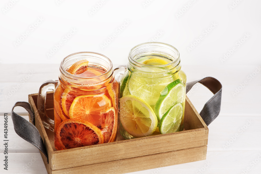 Two jars with citrus lemonades in the wooden box Two jars with citrus lemonades in the wooden box
