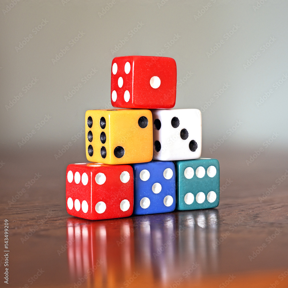 Tower of six colored dice with numbers from 1 to 6 on a wooden game table, soft background Tower of six colored dice with numbers from 1 to 6 on a wooden game table, soft background