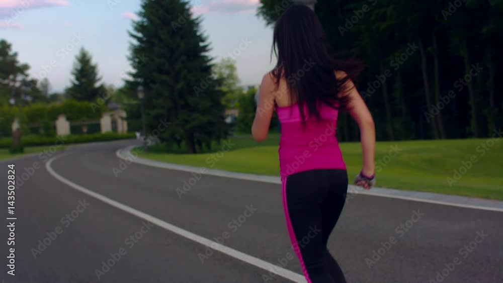 Sport woman running in city park. Woman running in slow motion. Running woman on park road. Outdoor fitness workout. Fitness training at morning. Back view of female runner with long hair Sport woman running in city park. Woman running in slow motion. Running woman on park road. Outdoor fitness workout. Fitness training at morning. Back view of female runner with long hair