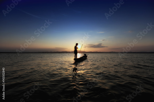 silhouette fisherman and boat in river on during sunset,Thailand