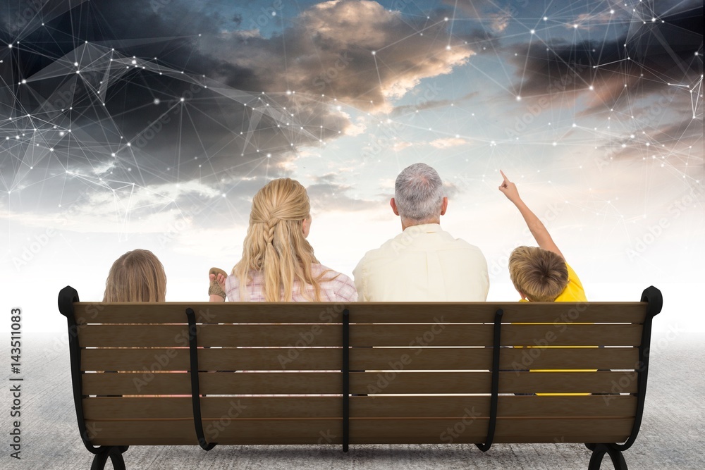 Naklejka premium Rear view of family sitting on bench against star constellations