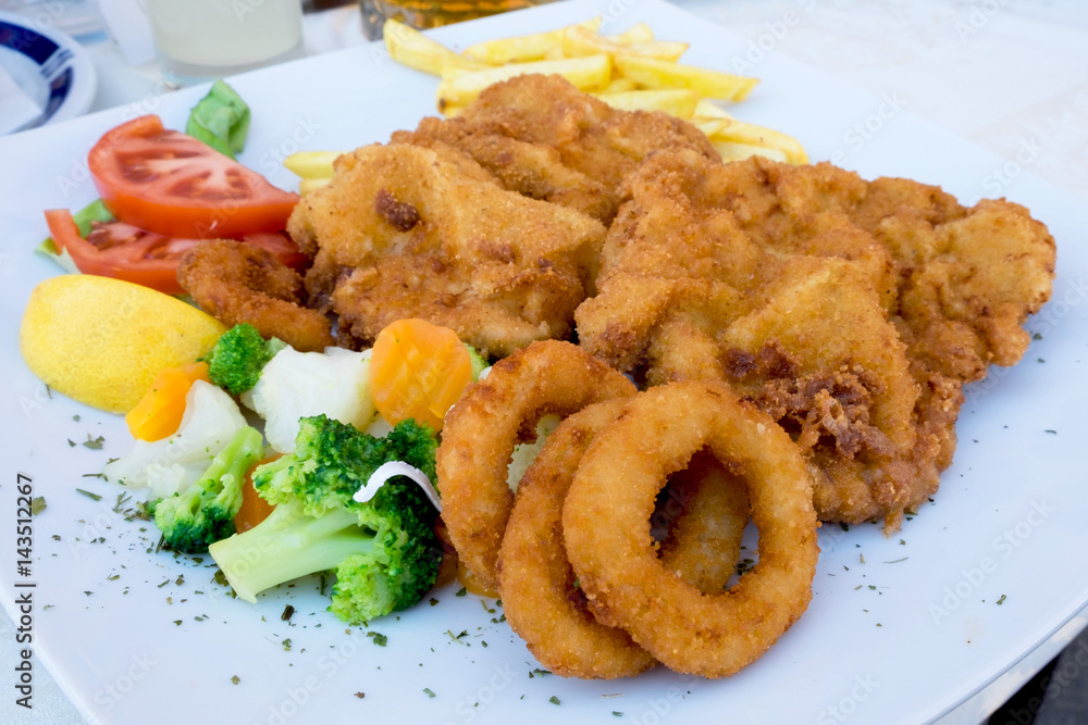Vienna schnitzel with onion rings and quickly boiled vegetables served at the restaurant in Sombor, Serbia Vienna schnitzel with onion rings and quickly boiled vegetables served at the restaurant in Sombor, Serbia