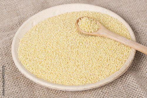 Yellow millet seeds in a wooden bowl on the table