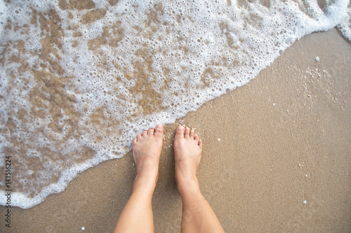 foot of human on sand and soft wave on the sea.