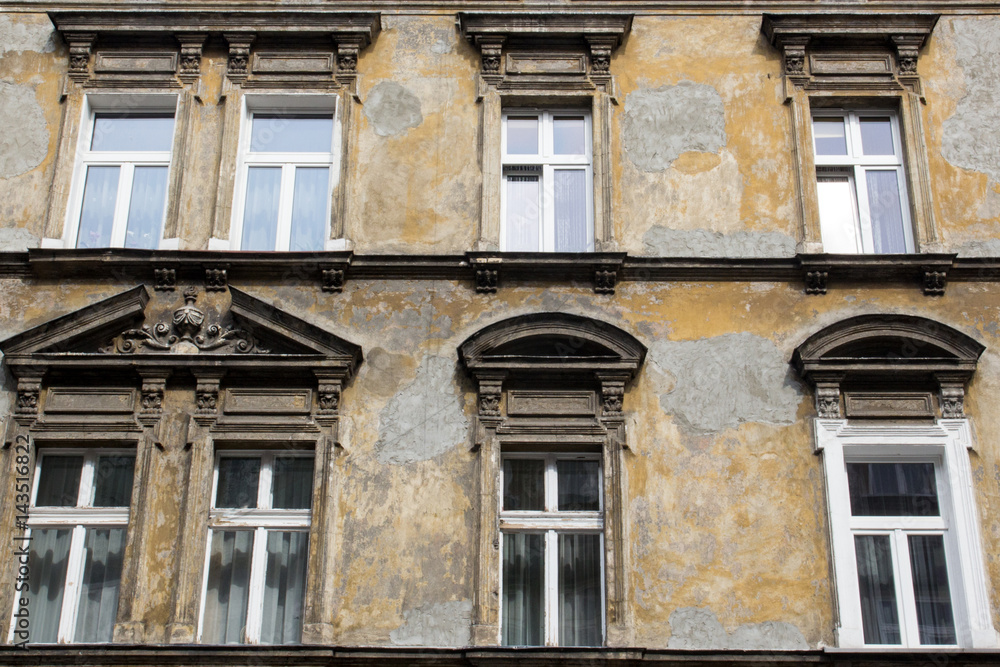 Obraz premium Six windows on the facade of the ragged old house