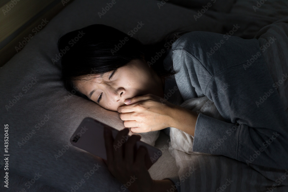 Woman feeling tired and using mobile phone on bed Woman feeling tired and using mobile phone on bed