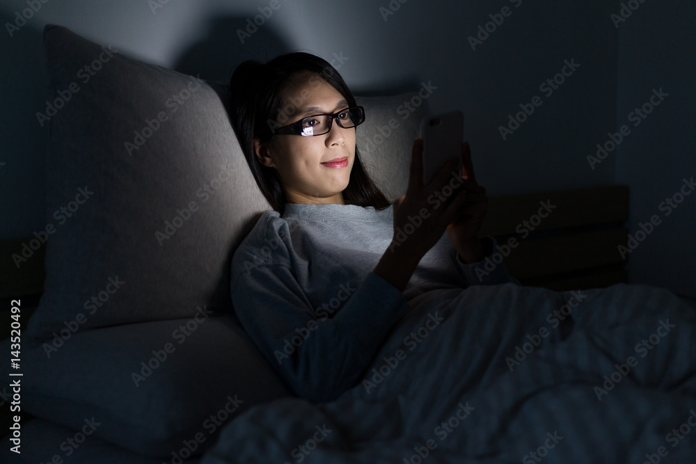 Obraz premium Woman watching on mobile phone at night