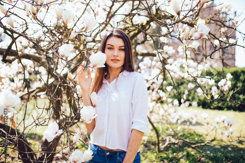 Beauty woman standing on background Magnolia blossoming flowers. Spring season photo