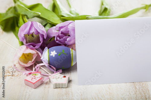 Fototapeta Naklejka Na Ścianę i Meble -  Bouquet purple tulips,paper and Easter eggs on a light wooden table.