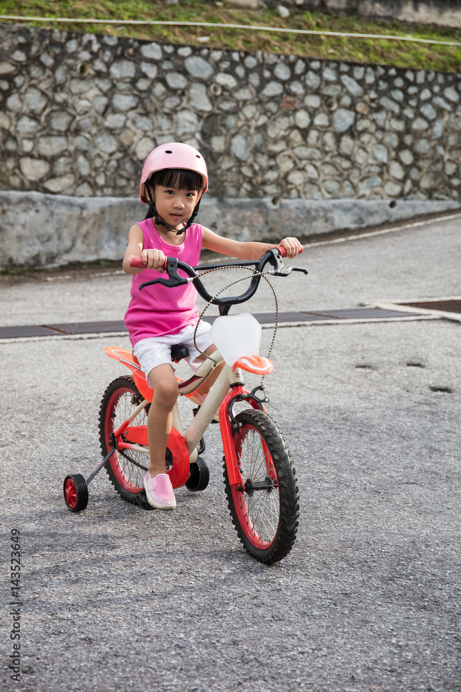 Asian Chinese little girl riding bicycle on tar road