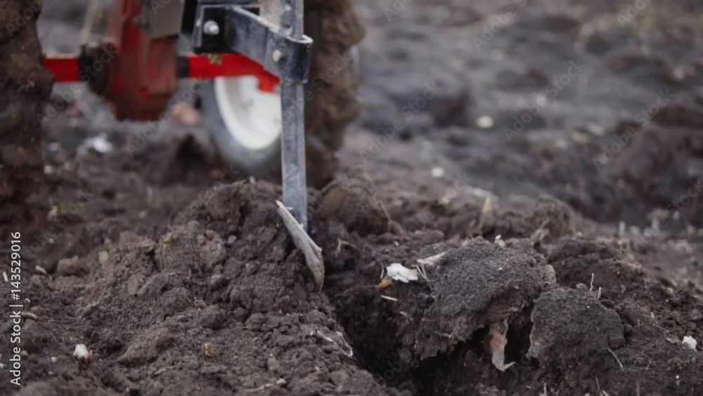 Closeup view of a cultivator tiller preparing garden soil, new seeding season on organic home vegetable farm. Shot in slowmotion Closeup view of a cultivator tiller preparing garden soil, new seeding season on organic home vegetable farm. Shot in slowmotion