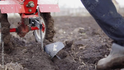 Wallpaper Mural Closeup view of a cultivator tiller preparing garden soil, new seeding season on organic home vegetable farm. Man pooling it forward. Shot in slowmotion Torontodigital.ca