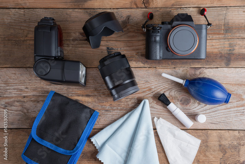 Tools for cleaning camera with dslr camera and lens, flash. Different objects on wooden background.