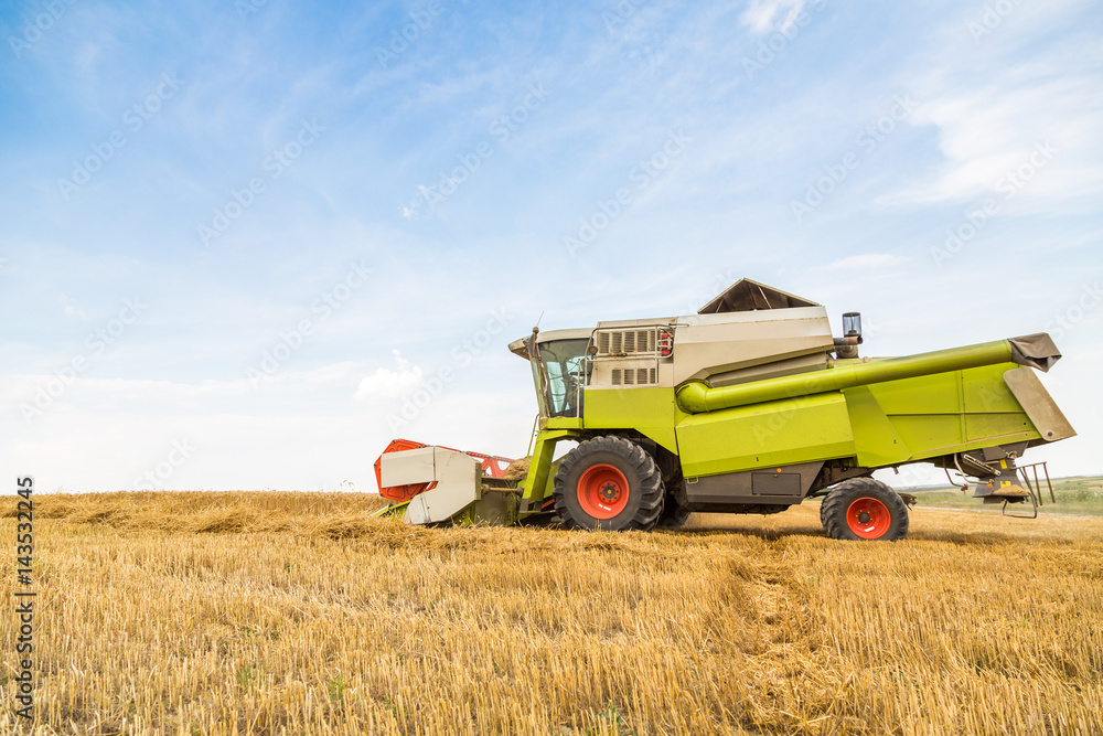 Combine harvester in action on wheat field. Harvesting is the process of gathering a ripe crop from the fields. Combine harvester in action on wheat field. Harvesting is the process of gathering a ripe crop from the fields.