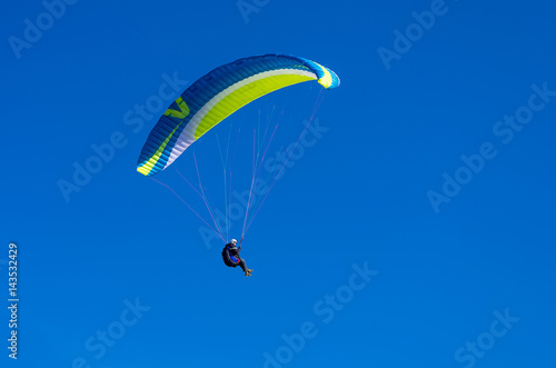 The paraglider flies in the blue sky