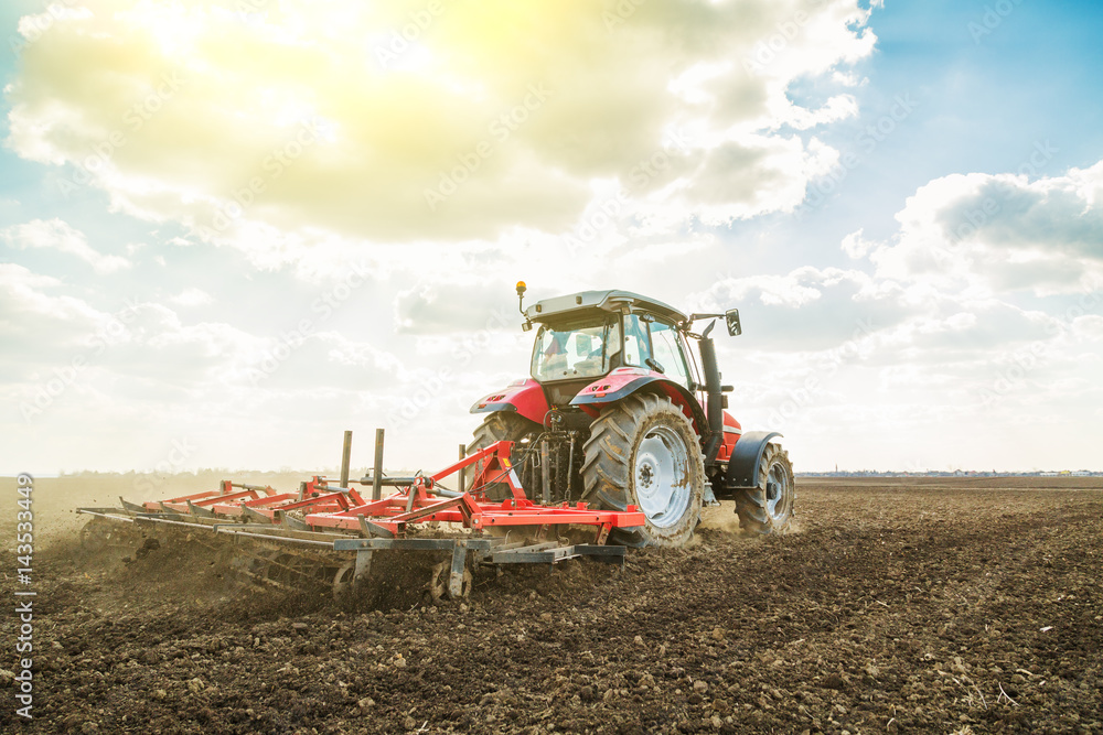Fototapeta premium Farmer in tractor preparing land with seedbed cultivator as part of pre seeding activities in early spring season of agricultural works at farmlands.