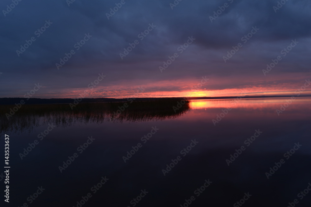 Bright sunset light above the surface of the water in a cloudy sky