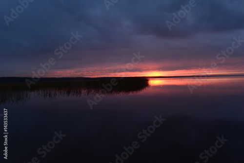 Bright sunset light above the surface of the water in a cloudy sky