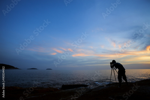 Silhouette of a photographer or traveler using a professional DSLR camera photographer take sunset photo
