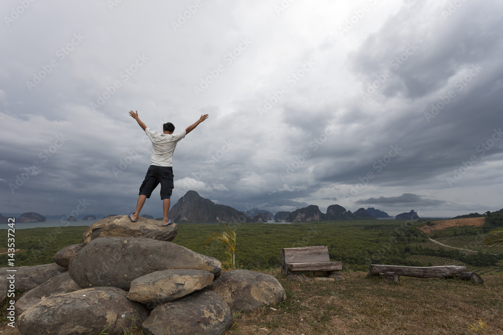Man standing on big stone holding his hand up and see landscape view in bad weather day. Man standing on big stone holding his hand up and see landscape view in bad weather day.