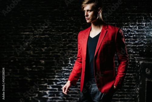 The guy is a model in a red jacket. Beautiful brown-haired man on a black background. photo