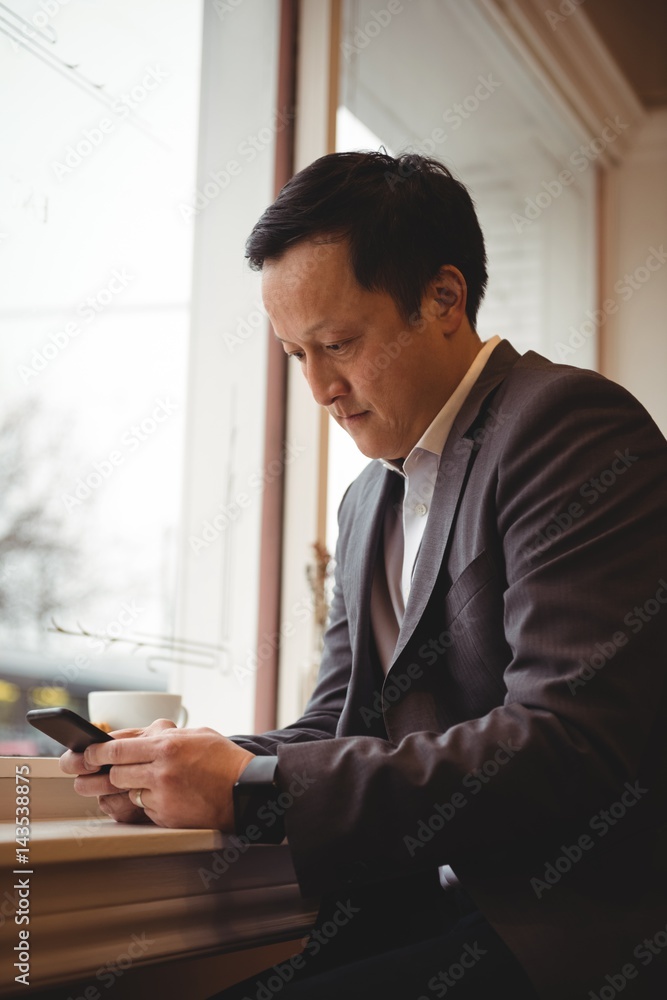Businessman using mobile phone in coffee shop Businessman using mobile phone in coffee shop
