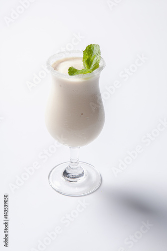 Delicious milkshake with a leaf of mint on top on a white background