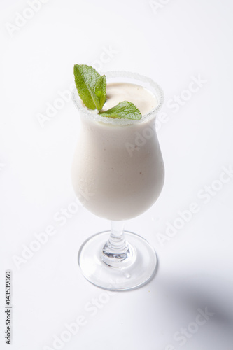 Delicious milkshake with a leaf of mint on top on a white background