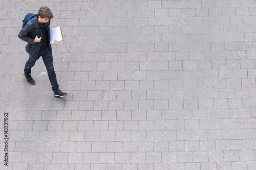 Young man with backpack and headphone going to school college university from above