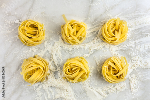 Overhead photo of pasta nests on white marble