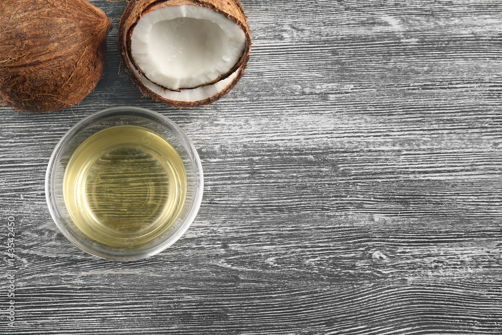 Glass bowl with oil and coconut on grey wooden background Glass bowl with oil and coconut on grey wooden background