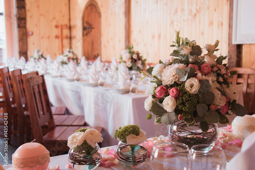 Stylishly decorated wedding table with flowers, candles, rose petals in pink colors. Flower arrangement