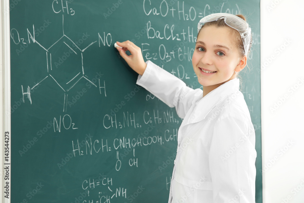 Beautiful school girl standing at chalkboard in chemistry class
