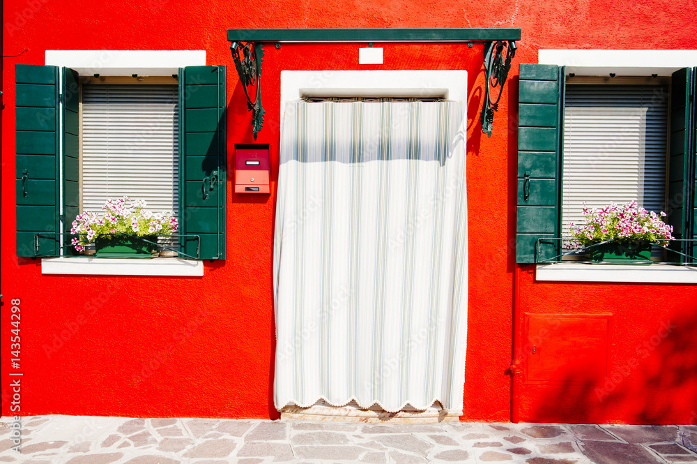 Fototapeta premium Beautiful house facade on Burano island, north italy. Colorful red old damaged wall with a door and windows