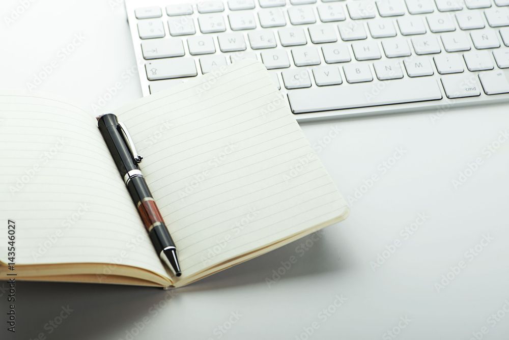 Open notepad and pen next to keyboard on white background. Open notepad and pen next to keyboard on white background.